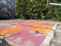 an outdoor basketball court in a large apartment complex with graffiti on it's surface