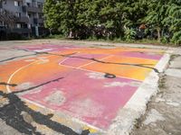 an outdoor basketball court in a large apartment complex with graffiti on it's surface