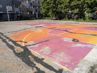 an outdoor basketball court in a large apartment complex with graffiti on it's surface