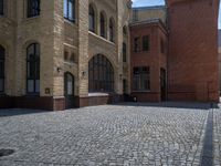 the sidewalk is paved with stones and has a bench in front of it, with no people inside