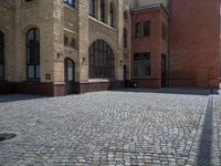 the sidewalk is paved with stones and has a bench in front of it, with no people inside