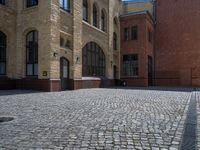 the sidewalk is paved with stones and has a bench in front of it, with no people inside