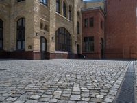 the sidewalk is paved with stones and has a bench in front of it, with no people inside