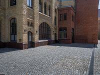 the sidewalk is paved with stones and has a bench in front of it, with no people inside