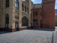 the sidewalk is paved with stones and has a bench in front of it, with no people inside