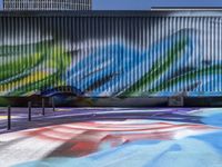 the bench and colorful wall mural make a striking background in this urban space, with no walls