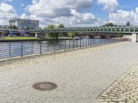 a path along the river with metal railings and buildings along it below the water