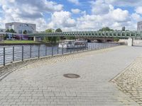 a path along the river with metal railings and buildings along it below the water