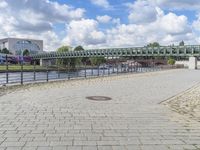 a path along the river with metal railings and buildings along it below the water