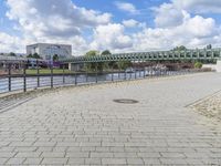 a path along the river with metal railings and buildings along it below the water