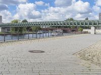 a path along the river with metal railings and buildings along it below the water