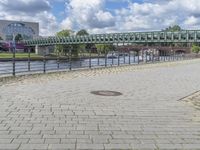 a path along the river with metal railings and buildings along it below the water