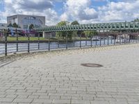 a path along the river with metal railings and buildings along it below the water