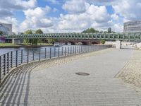 a path along the river with metal railings and buildings along it below the water