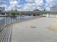 a path along the river with metal railings and buildings along it below the water