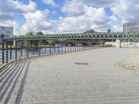 a path along the river with metal railings and buildings along it below the water