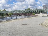 a path along the river with metal railings and buildings along it below the water