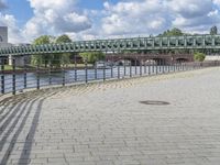 a path along the river with metal railings and buildings along it below the water