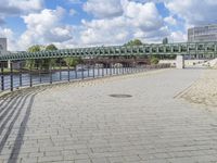 a path along the river with metal railings and buildings along it below the water