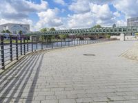 a path along the river with metal railings and buildings along it below the water