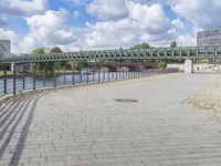 a path along the river with metal railings and buildings along it below the water