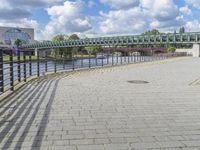 a path along the river with metal railings and buildings along it below the water