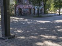 a red fire hydrant sitting in front of a brick street corner and buildings with graffiti all over it