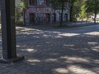 a red fire hydrant sitting in front of a brick street corner and buildings with graffiti all over it