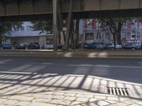 the shadow of a bridge over a road below the bridge over looking a street filled with cars