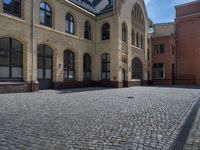 the sidewalk is paved with stones and has a bench in front of it, with no people inside