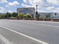 the empty road is next to a city street in this picture, there is a clock and statue