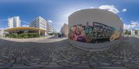 a fish eye lens is view of a building on the left and graffiti on the right