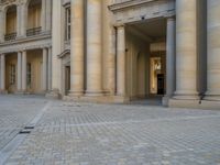 a courtyard with a building on the other side and a large white building with many windows