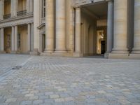 a courtyard with a building on the other side and a large white building with many windows