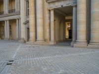 a courtyard with a building on the other side and a large white building with many windows