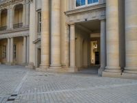 a courtyard with a building on the other side and a large white building with many windows