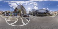 fish eye view of intersection with urban buildings in background and graffiti on the wall along street