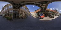 fisheye image of a small train and buildings with the door open in a european setting