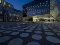 the exterior of a building has circles on it as it sits next to other buildings