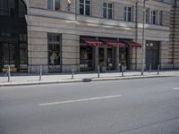 a parking meter next to an old building and parked car with red awnings