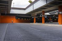 cars in an outside parking lot with two columns and one red and orange columned structure