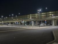 some lights on poles over a street in front of a building at night at the airport