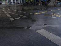 a wet street with two signs painted in yellow on it and a cross walk across the street