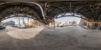 a fish eye photo of the side view of a subway train at an intersection with a few people