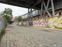 a sidewalk near a building covered in graffiti and graffiti writing on the walls of it