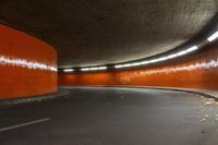 the tunnel under the highway at night has an orange wall and flooring with light