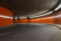 the tunnel under the highway at night has an orange wall and flooring with light