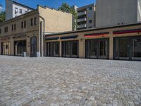 the sidewalk is paved with stones and has a bench in front of it, with no people inside