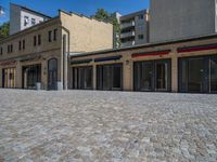 the sidewalk is paved with stones and has a bench in front of it, with no people inside