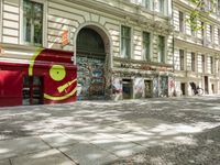 a restaurant in the middle of a narrow city street with graffiti on the wall and the sidewalk outside the building